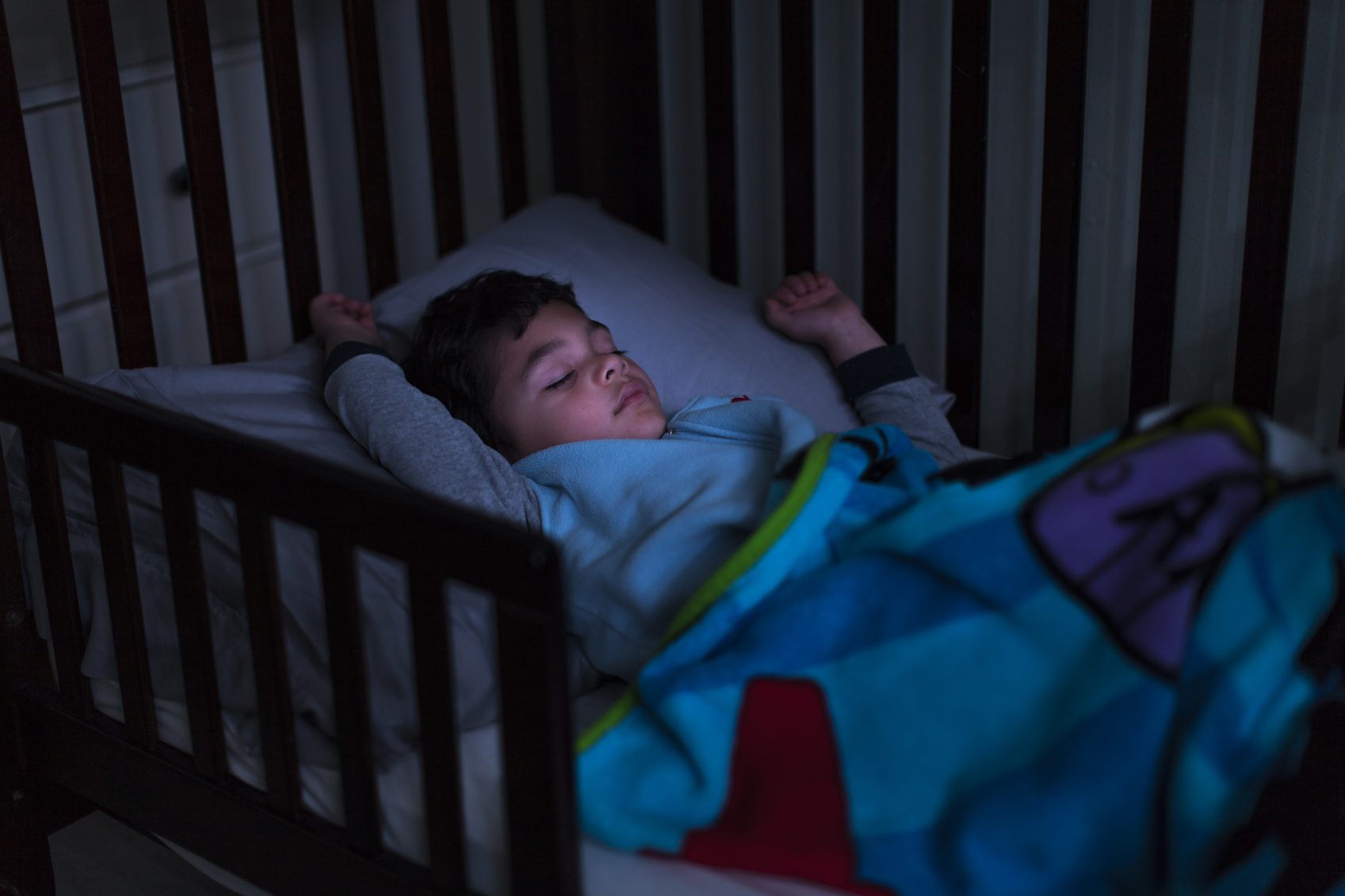 Stock photo of a young handsome boy sleeping in a bed with light on his face