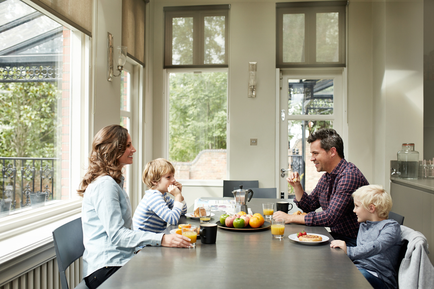Shot of a smiling family of four eating breakfast together in their kitchen